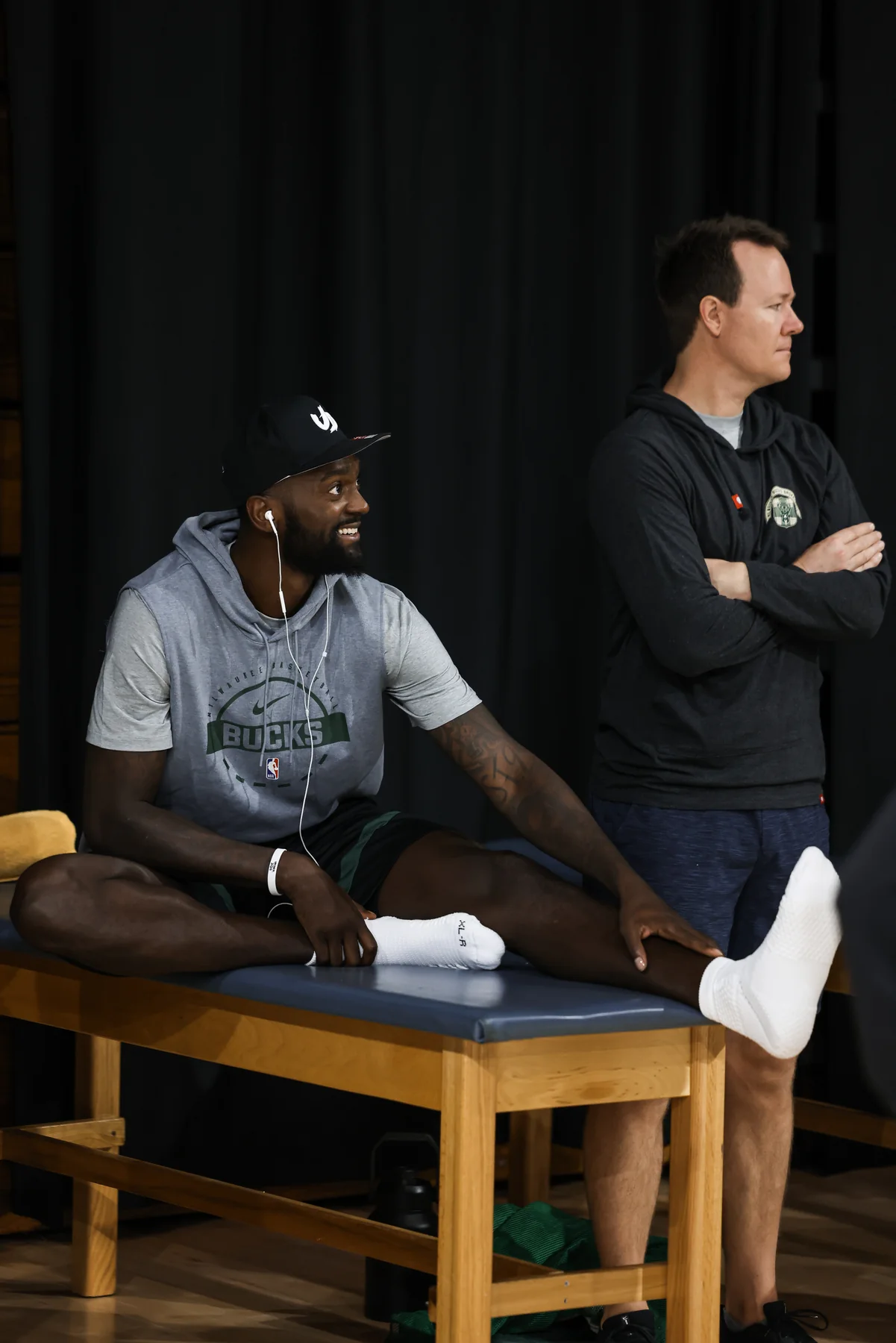 Milwaukee Bucks player seated beside a staff member during 2025 training camp in Miami